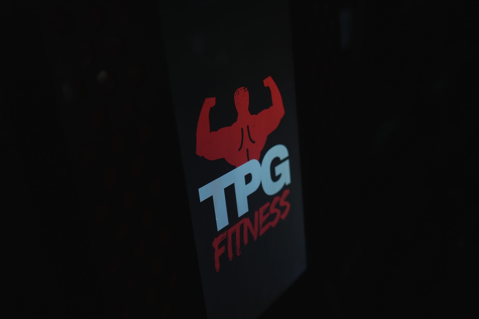 Angled close-up of the TPG Fitness logo panel on the kiosk enclosure