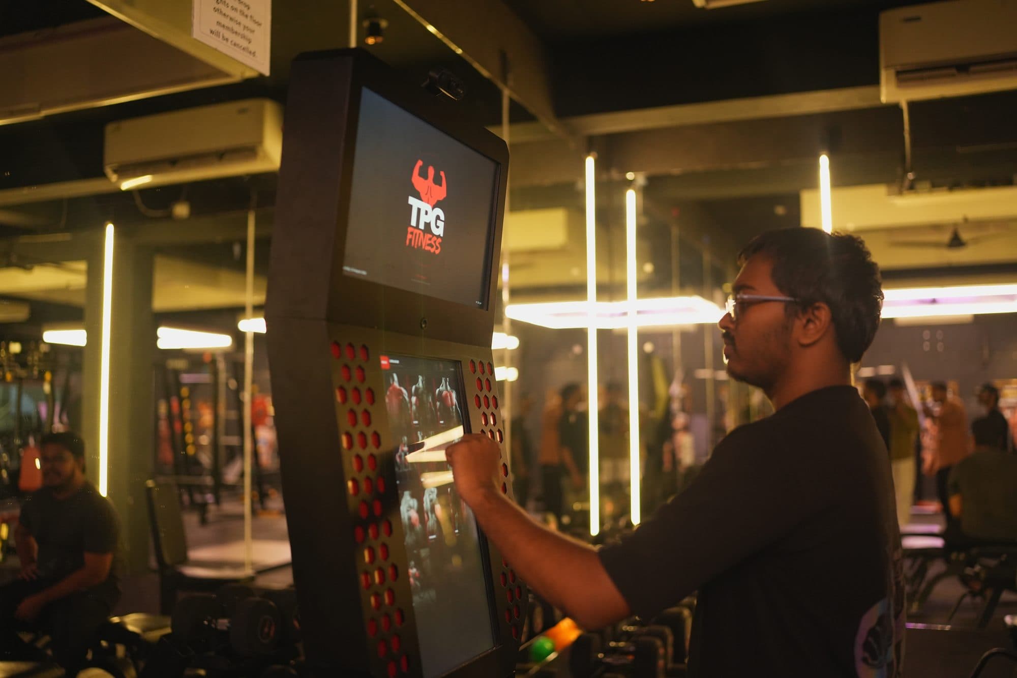 A gym member tapping the kiosk touchscreen to start a workout