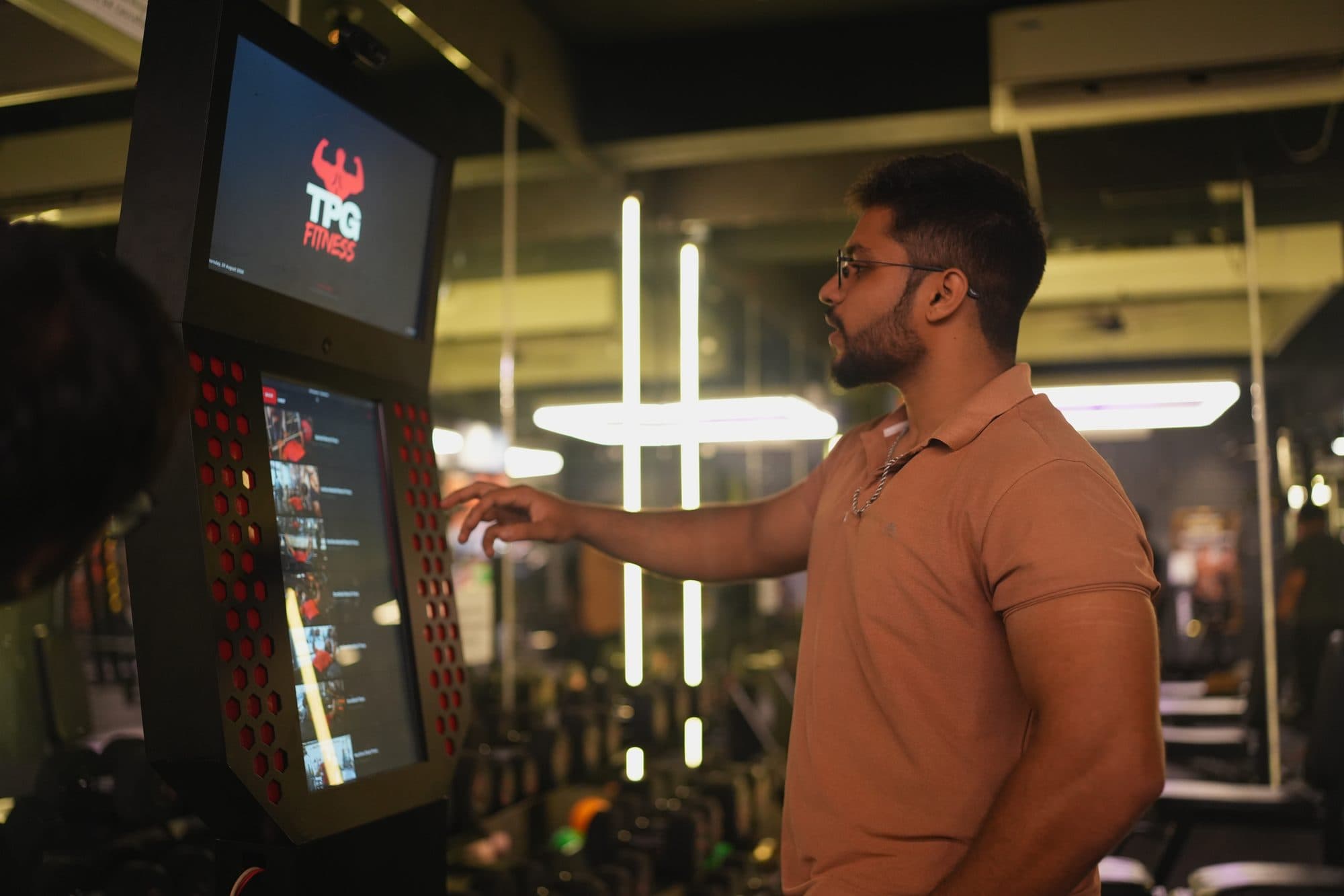A gym member in profile reading an exercise walkthrough on the kiosk screen
