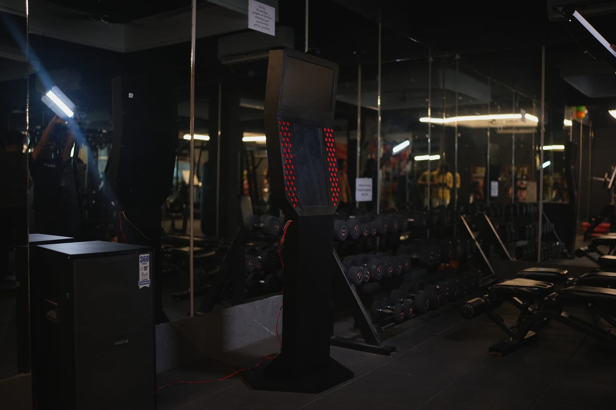 The kiosk on the gym floor at dusk light with a lens flare across the frame